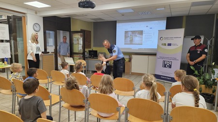Policist je enemu od otrok nadel svoj jopič. 